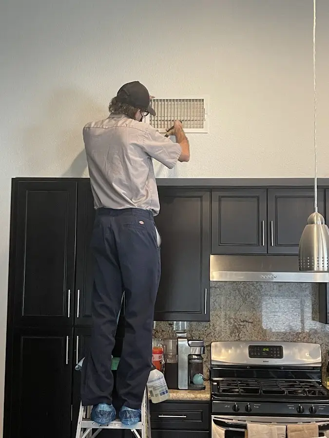 Technician inspecting an air vent during HVAC service in Alexandria